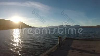 山岛上美丽的日出，有波浪形峡湾和木墩的倒影