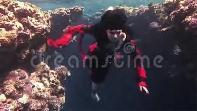 在红海珊瑚的背景下，自由<strong>潜水</strong>者穿着红色<strong>衣服</strong>。