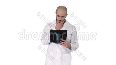医生在白色背景下行走时检查肺部X线片。