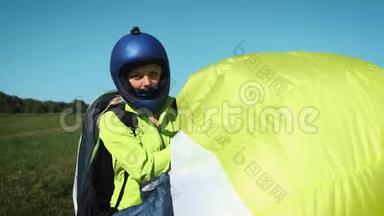 滑翔伞女孩。 滑翔伞准备在一座绿色的小山上起飞。 着陆后携带降落伞。