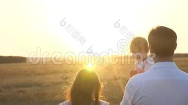 日落时分，爸爸和妈妈和她的女儿抱在怀里散步。 一家人在日落时带着一个孩子散步。 有女儿的父亲