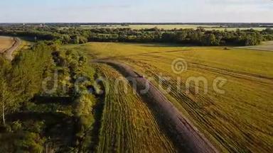 飞越一条乡村景观道路.. 耕地。 空中拍摄了一条带着车的乡村公路。