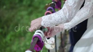 新婚夫妇手中的装饰锁。 剪辑。 婚礼象征着永恒的爱，锁在新娘和新郎的手中