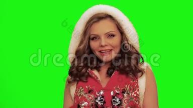 穿着圣诞服装的漂亮女人一边唱歌一边跳舞，一边看着镜头里的镜头，一边对着色彩。