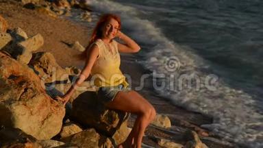 坐在亚得里亚海多岩石的海滩上，头发飞扬的年轻女子