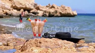 埃及海滩上的一种带稻草的玻璃中的热带<strong>鲜榨果汁</strong>矗立在海边的岩石上。 慢动作