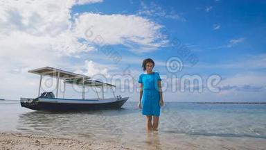 穿着绿松石服装的漂亮黑发女子站在大海中，背景是传统的巴厘岛船。 适合
