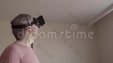 灰发男人在家玩他的手机虚拟现实耳机。 廉价的VR面具在行动。 4Ksteatam