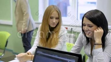 <strong>学生们</strong>在教室里看笔记本<strong>电脑</strong>。 练习经济学课。 黑发女孩微笑。