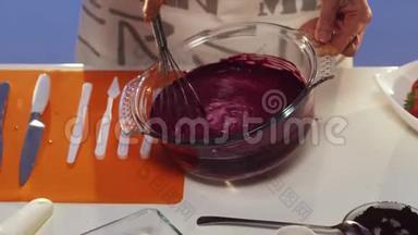 白色桌子上用大圆形玻璃锅手工搅拌紫罗兰物质