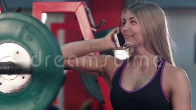 在健身房减肥室里，一个微笑健康的女人在打电话