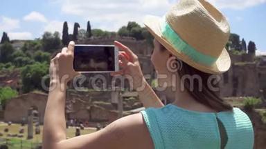 女士靠近论坛罗曼努姆在手机上拍照。 女游客拍照罗马论坛