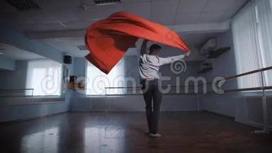 穿着灰色套头衫的<strong>舞蹈学校</strong>的一名年轻学生通过了一项考试，显示出与红色纺织物一起的引人注目的现代<strong>舞蹈</strong>