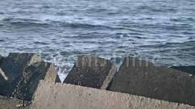 混凝土防波堤。 水溅在码头岩石上。 海浪撞击岩石