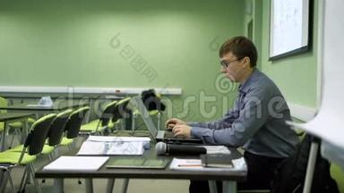 讲师讲课前，打印<strong>讲稿</strong>.. 戴眼镜的年轻人空着手提电脑