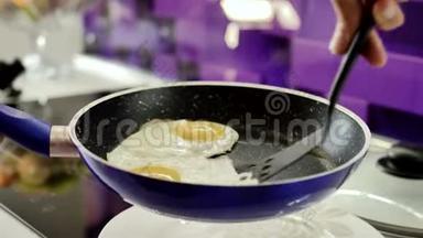 女人的手把炒鸡蛋放在锅里，试图把食物和菜肴分开