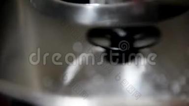 在专业搅拌机的碗中搅拌奶油的过程。 图像失去焦点。 边缘运动