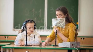 在教室里使用耳机和麦克风的年轻女孩和老师