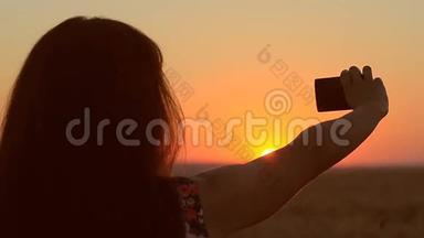 女孩带着手机在日落图上打着电话，夕阳美丽的黄昏景观。
