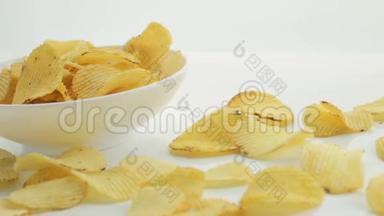一个男人手里拿着碗里的薯片，不健康的有害食物，黄色美味的土豆肋条脆片随机躺着