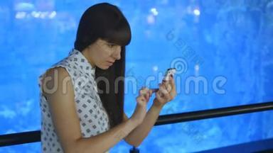 年轻女子在海洋馆<strong>玩</strong>口袋妖怪，使用智能<strong>手机</strong>。 女孩<strong>玩</strong>流行的智能<strong>手机</strong>游戏-捕捉