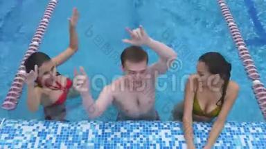 两个快乐的年轻女人和一个在游泳池里玩的年轻人