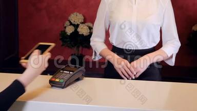 女士用智能手机支付酒店费用，接待员给电子钥匙。 4K.