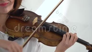 女孩用手指弹奏小提琴的琴弦。 快关门。 白色背景