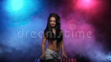 DJ女孩带着耳机跳舞，在烟雾中旋转碟片