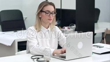 年轻女子集中精力在办公室桌上的笔记本电脑上打眼镜