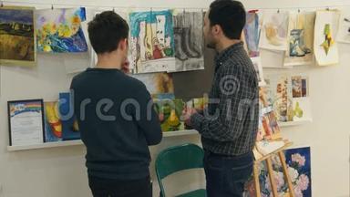 两个年轻人在讨论<strong>艺术</strong>学生画的画