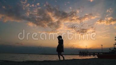 日落时分，一个迷人的<strong>女孩</strong>赤脚在沙滩上散步的肖像。 一个漂亮<strong>女孩</strong>的<strong>剪影</strong>
