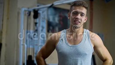 在健身房里，一个男人看着镜子，用<strong>肌肉</strong>发达的<strong>手臂</strong>摆动