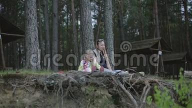 小女孩和她怀孕的母亲坐在森林里的悬崖上，把锥子扔下来。