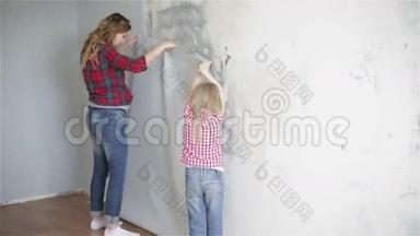 母亲和女儿穿着格子衬衫，正试着在<strong>墙上贴</strong>一张新墙纸。