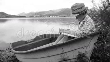 一个<strong>男孩</strong>坐在渔船上<strong>看书</strong>的黑白视频
