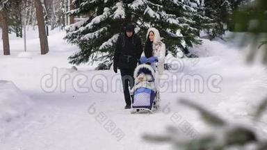 冬季散步。 一家人在冬季公园散步。 她把婴儿车里的婴儿卷起来。 新鲜空气对