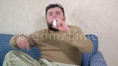 一个感冒的人坐在沙发上。 他在鼻子里喷了一种特殊的鼻腔喷雾剂。