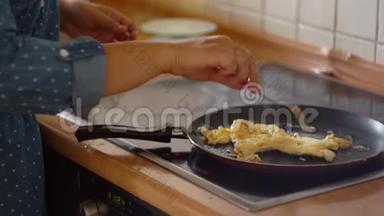 在煎锅里煎鸡蛋.. 有用的早餐，电磁炉，家庭主妇.. 厨房，做饭，炒鸡蛋.. 特写镜头。