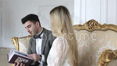 一对年轻夫妇正坐在一张<strong>老式沙发</strong>上翻看相册。