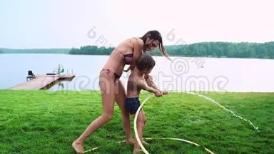 妈妈和儿子在<strong>草坪</strong>上玩耍，倒着水，笑着在<strong>操场</strong>上玩，草地上的背景是