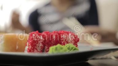 两个幸福的女人在日本料理<strong>餐厅</strong>吃寿司，用筷子。 <strong>盘子</strong>上的特写卷