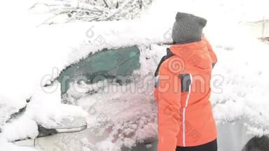一位年轻女子在大雪纷飞后，在汽车挡风玻璃上擦雪擦冰