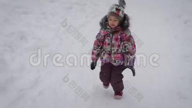 小女孩在冬天森林的小径上奔跑。 宝宝穿得很暖和，在树林里的时间会很愉快