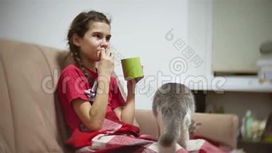 少女吃三明治喝茶看电视。 女孩吃三明治猫想吃东西