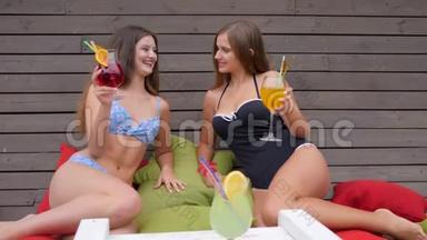 穿着泳衣的女朋友喝着饮料，坐在五颜六色的<strong>垫子</strong>上，参加母鸡聚会，穿着泳衣的女孩子喝着鸡尾酒。
