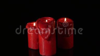 关闭3支点燃的红色蜡烛，围绕黑色背景旋转