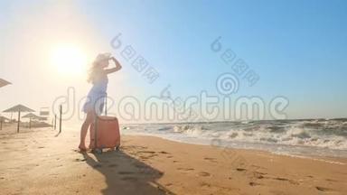 一个年轻的女人带着一个手提箱坐在海滩上。 一个年轻的女孩带着一个轮式手提箱沿着海滩散步。 <strong>一路</strong>走来