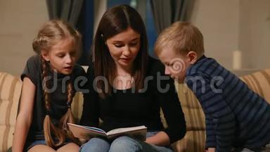 妈妈和他的女儿和小儿子一起坐在沙发上，一边在沙发上看故事