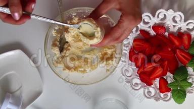 一个女人用奶油填充烹饪注射器。 碟子旁边是一个草莓。